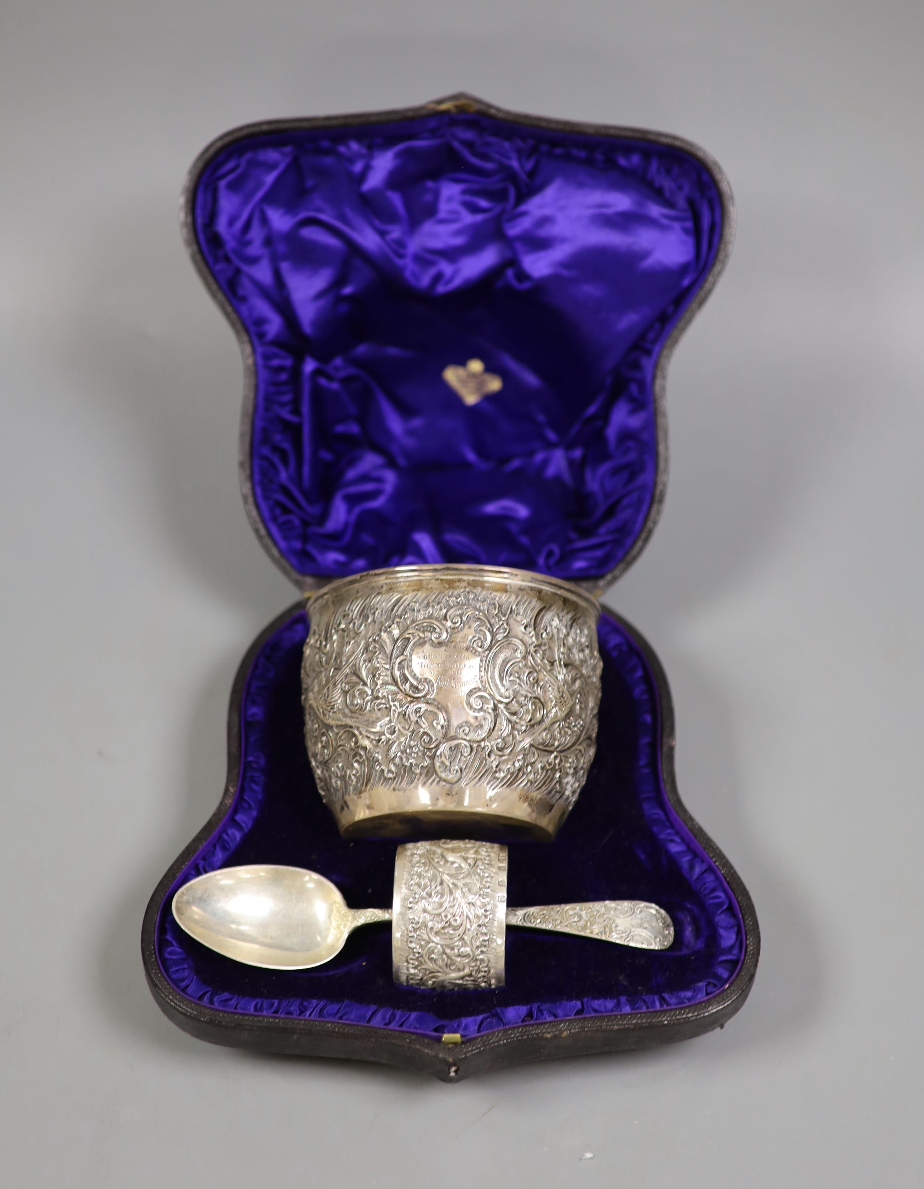 A cased late Victorian embossed silver christening bowl, spoon and napkin ring, Aird & Thomson, Glasgow, 1896, bowl 10.7cm, 7.5oz.